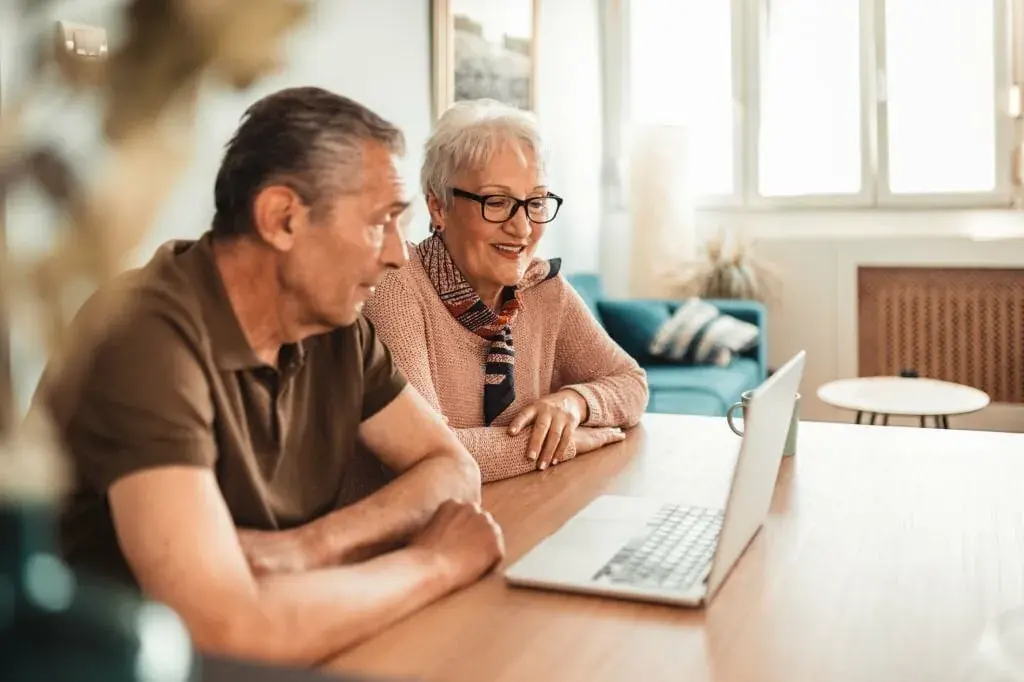 An older couple at a laptop, talking through their wellness plan