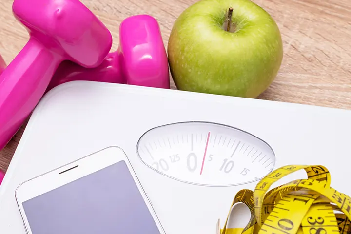 Hand weights, a bathroom scale, an apple and a tape measure